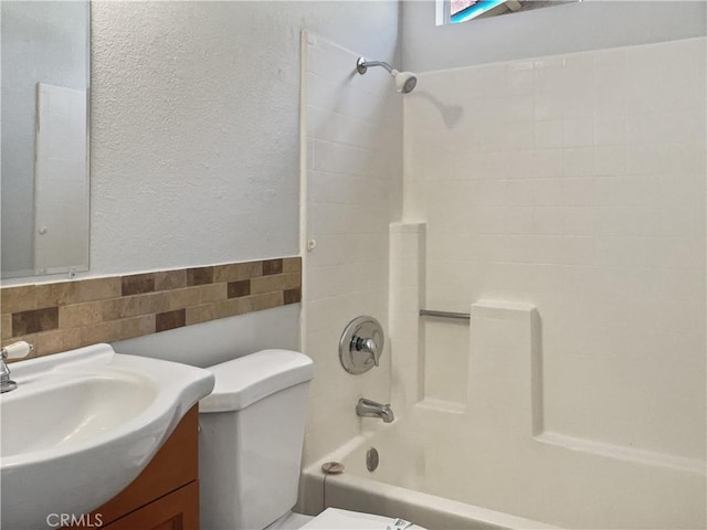 bathroom with toilet, washtub / shower combination, tile walls, and vanity