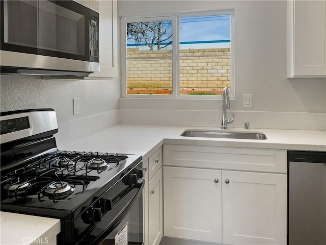 kitchen featuring appliances with stainless steel finishes, light countertops, white cabinets, and a sink