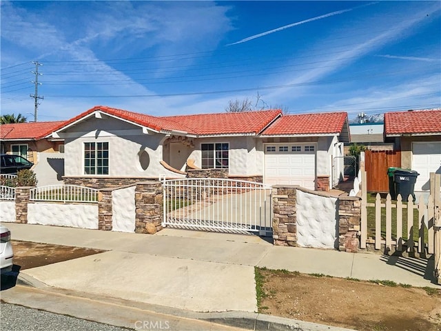 view of front facade with driveway, a fenced front yard, a garage, and a tiled roof