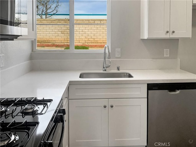 kitchen with dishwasher, black range with gas stovetop, light countertops, white cabinetry, and a sink