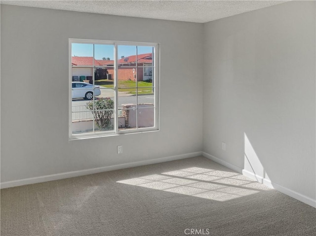 carpeted empty room featuring baseboards and a textured ceiling