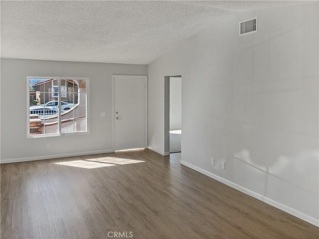 unfurnished room featuring a textured ceiling, wood finished floors, visible vents, and baseboards