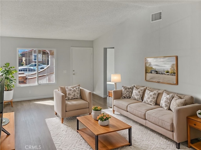 living room with visible vents, vaulted ceiling, a textured ceiling, and wood finished floors