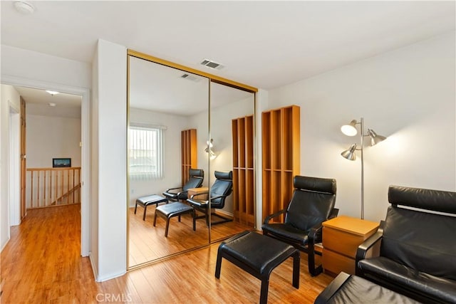 living area with light wood-style flooring, an upstairs landing, and visible vents