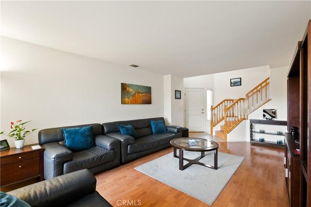 living area with light wood finished floors, visible vents, and stairs