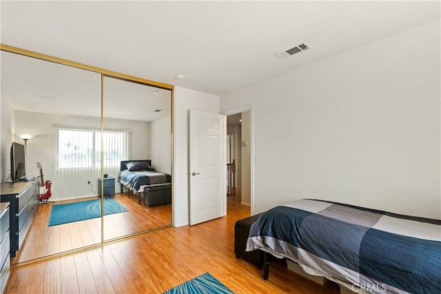 bedroom with a closet, visible vents, baseboards, and light wood-style floors