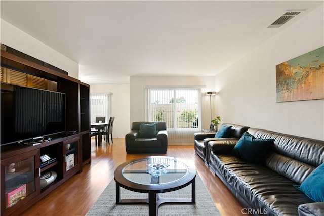 living area featuring visible vents and wood finished floors