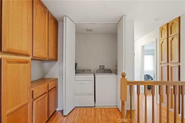 laundry area with laundry area, light wood-style floors, independent washer and dryer, and visible vents