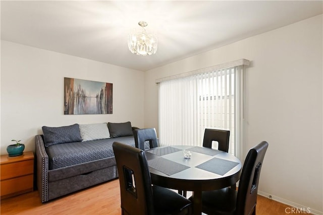 dining space featuring a chandelier, light wood-type flooring, and baseboards