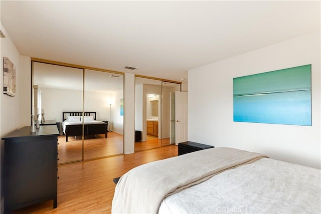 bedroom featuring visible vents, two closets, and light wood-style flooring