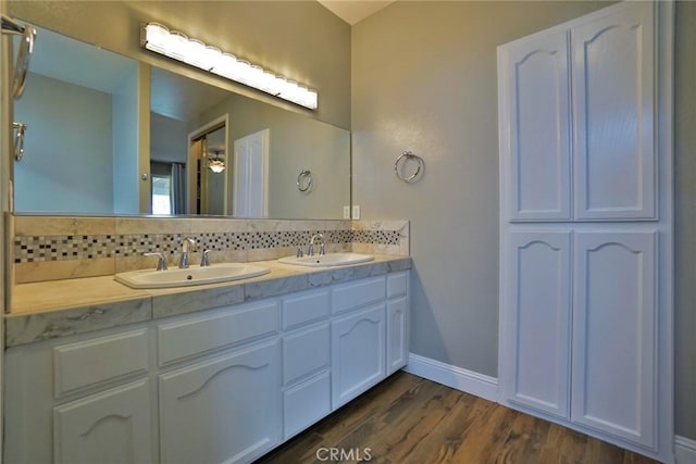 bathroom with double vanity, wood finished floors, backsplash, and a sink