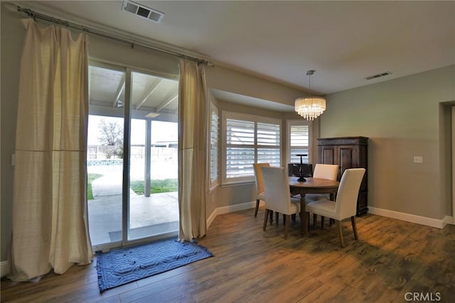 dining space featuring baseboards, visible vents, an inviting chandelier, and wood finished floors