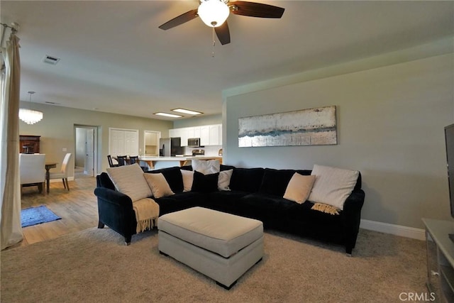 living room with a ceiling fan, visible vents, and baseboards