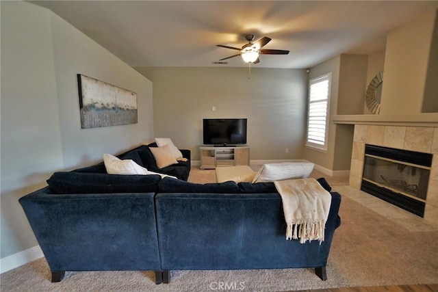 living area featuring a ceiling fan, a tile fireplace, visible vents, and baseboards