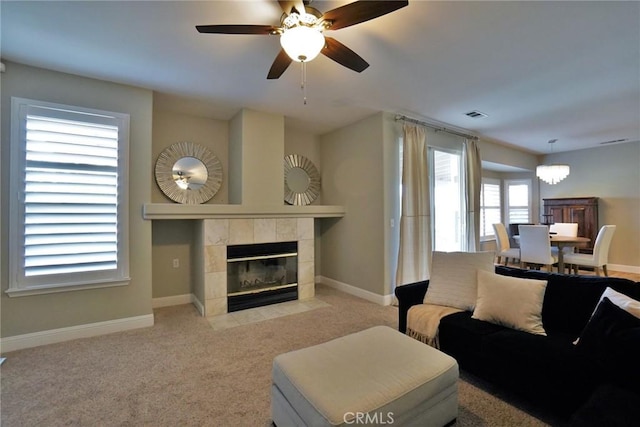 living area with carpet floors, baseboards, visible vents, and a tiled fireplace