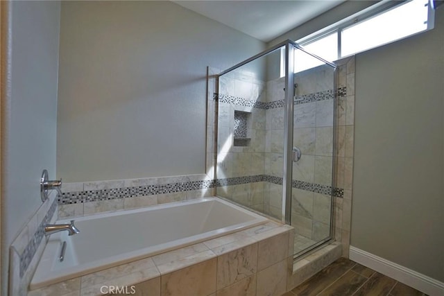 bathroom with a garden tub, wood finished floors, a shower stall, and baseboards