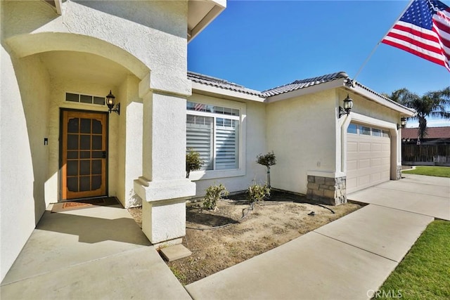 property entrance featuring a garage, driveway, and stucco siding