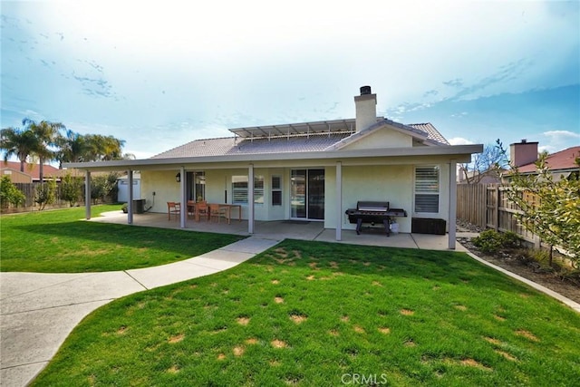 rear view of property with a yard, a chimney, stucco siding, a patio area, and a fenced backyard