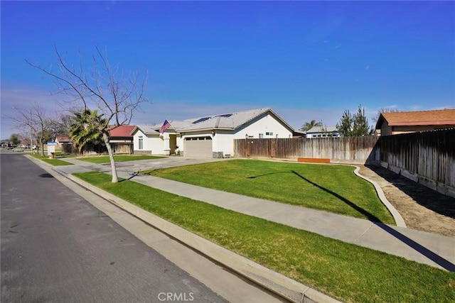 view of front facade with concrete driveway, fence, a front lawn, and an attached garage