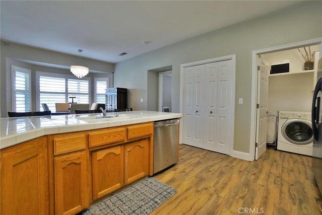 kitchen featuring light wood-style floors, tile counters, dishwasher, washer / clothes dryer, and brown cabinetry