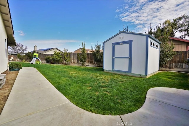 view of yard with a shed, a patio, a fenced backyard, and an outbuilding