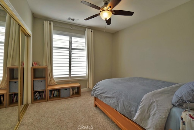 carpeted bedroom featuring ceiling fan, a closet, and visible vents