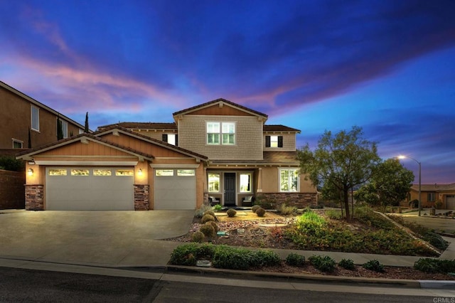 craftsman inspired home with a garage, driveway, and stone siding