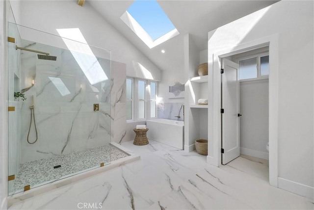 bathroom with a marble finish shower, a healthy amount of sunlight, a skylight, a freestanding tub, and marble finish floor