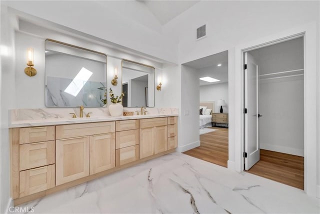 ensuite bathroom featuring a sink, double vanity, ensuite bathroom, visible vents, and a skylight
