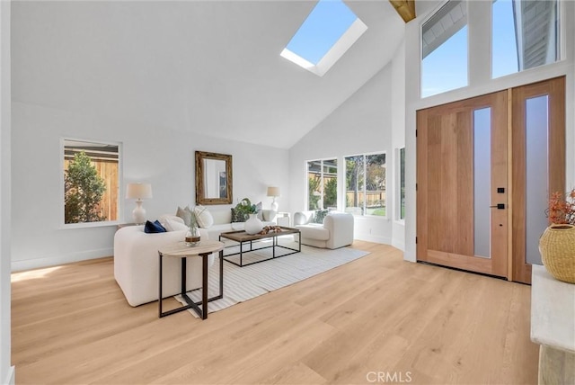 living area featuring a skylight, wood finished floors, baseboards, and high vaulted ceiling