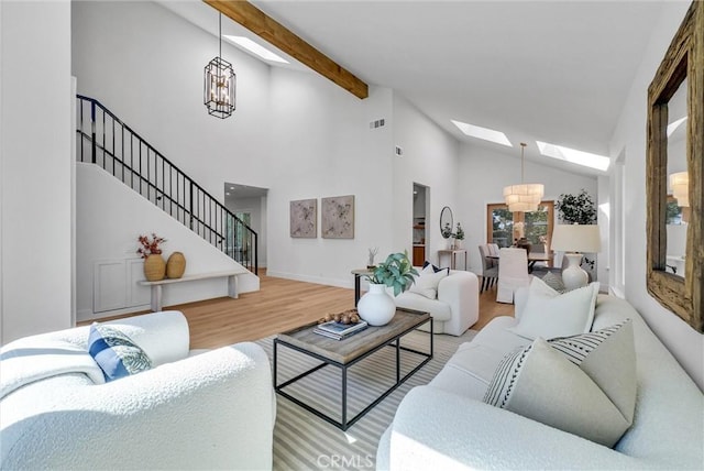 living room with high vaulted ceiling, a chandelier, wood finished floors, and a skylight