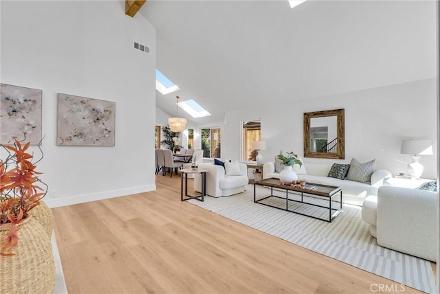 living area featuring visible vents, baseboards, a skylight, wood finished floors, and high vaulted ceiling