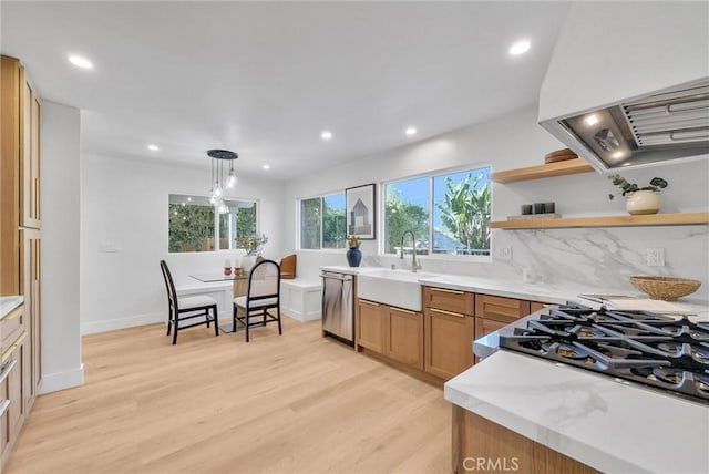 kitchen featuring open shelves, extractor fan, light wood-type flooring, stainless steel dishwasher, and a sink