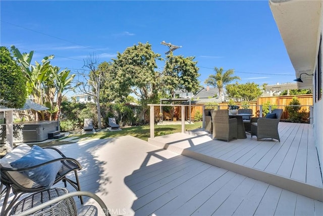 wooden terrace with a playground, a fenced backyard, outdoor dining space, and a hot tub