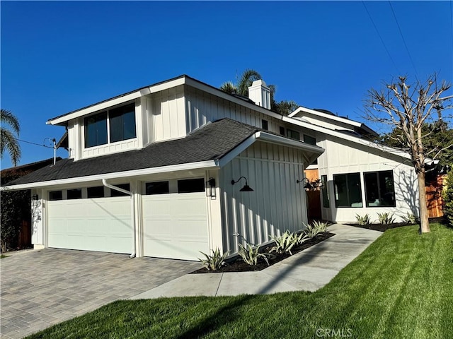 view of front of home featuring decorative driveway, a front lawn, board and batten siding, a garage, and roof with shingles