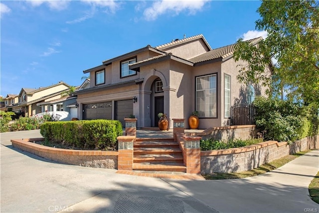 mediterranean / spanish house featuring a garage, a tile roof, and stucco siding