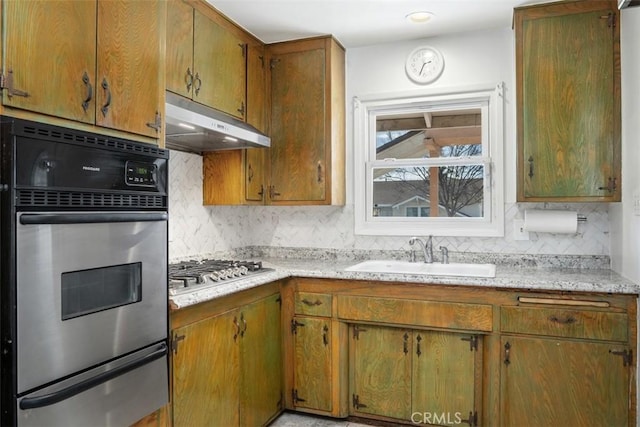 kitchen with under cabinet range hood, a sink, light countertops, appliances with stainless steel finishes, and a warming drawer