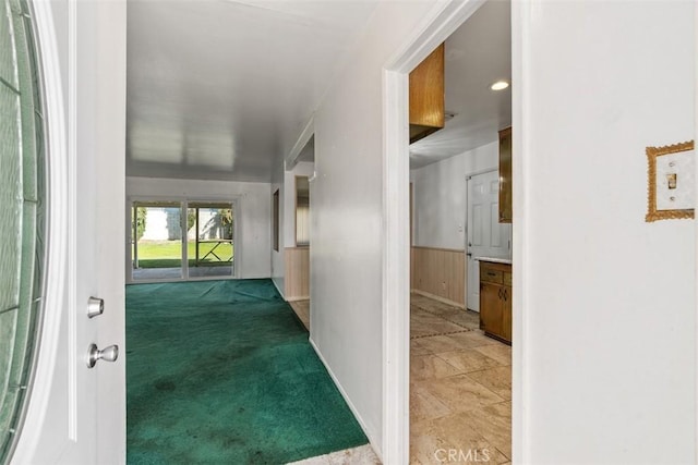 hallway with a wainscoted wall and carpet flooring