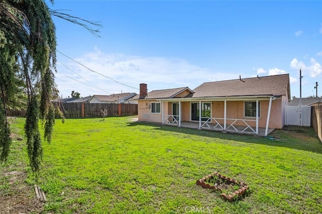 back of house with a fenced backyard, a lawn, and stucco siding