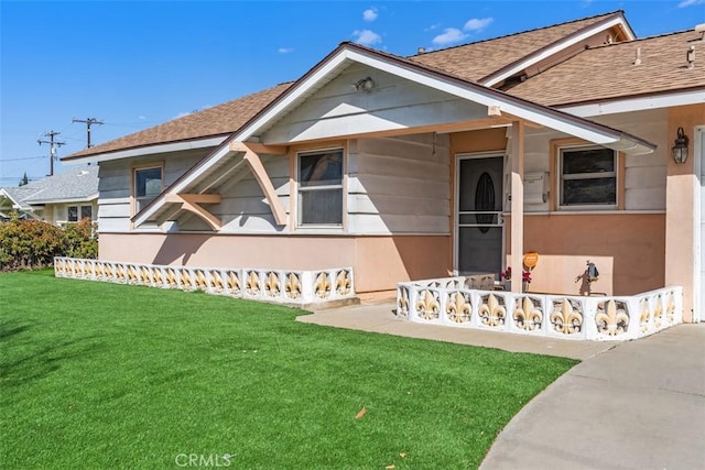 view of front facade with a front lawn and roof with shingles