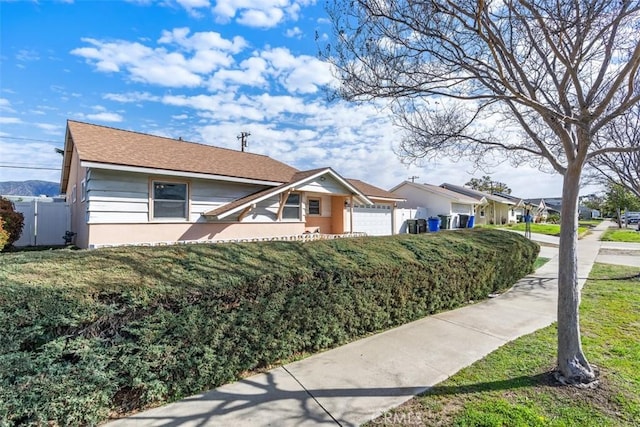 view of front of property featuring a front yard, fence, and an attached garage