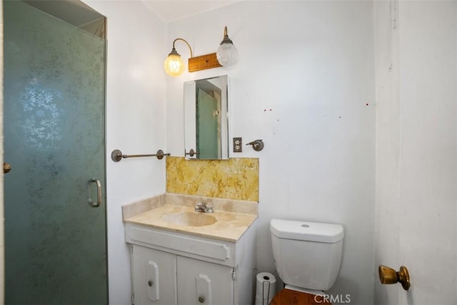 bathroom featuring vanity, a shower stall, and toilet