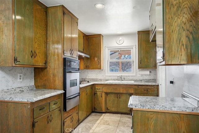 kitchen with a warming drawer, light countertops, a sink, and oven