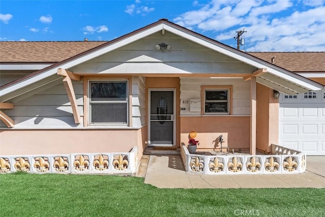 view of front of property featuring a garage, a shingled roof, a front yard, and stucco siding