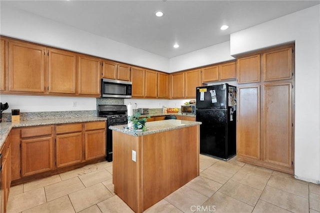 kitchen featuring black appliances, light stone counters, brown cabinetry, and a center island