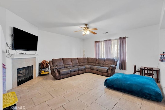 living area featuring light tile patterned floors, a fireplace, visible vents, and a ceiling fan