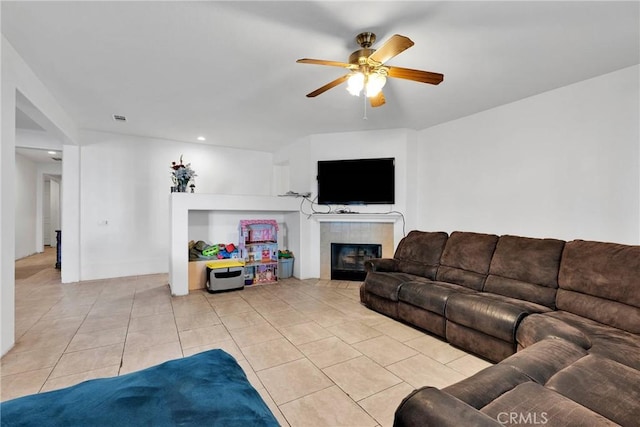 living area featuring light tile patterned floors, a tiled fireplace, and a ceiling fan