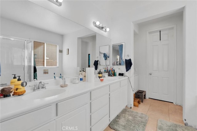 bathroom with double vanity, a shower with shower door, a sink, and tile patterned floors