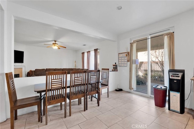 dining space with light tile patterned floors, a ceiling fan, and a tile fireplace