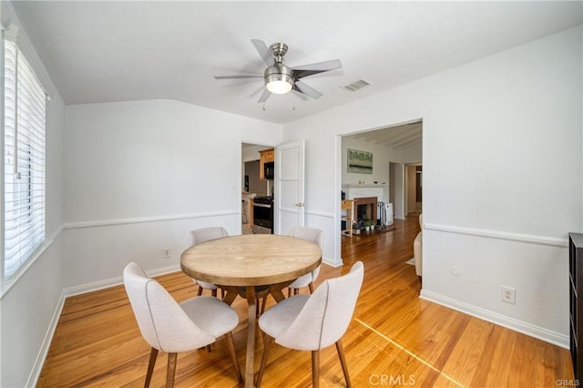 dining space featuring visible vents, baseboards, ceiling fan, light wood-type flooring, and a fireplace